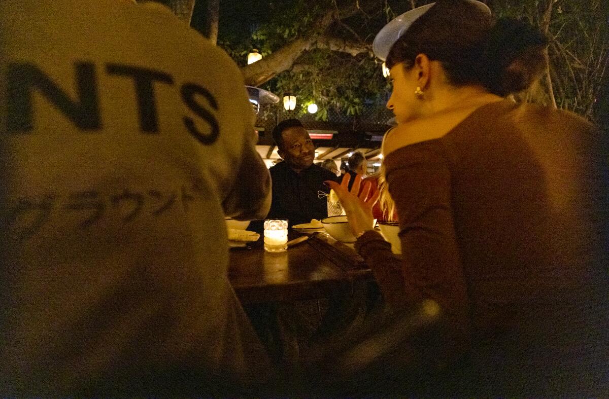 Jonathan Alexander listens to Cristina Haraba as they dine together with strangers at Bacari in Los Angeles 