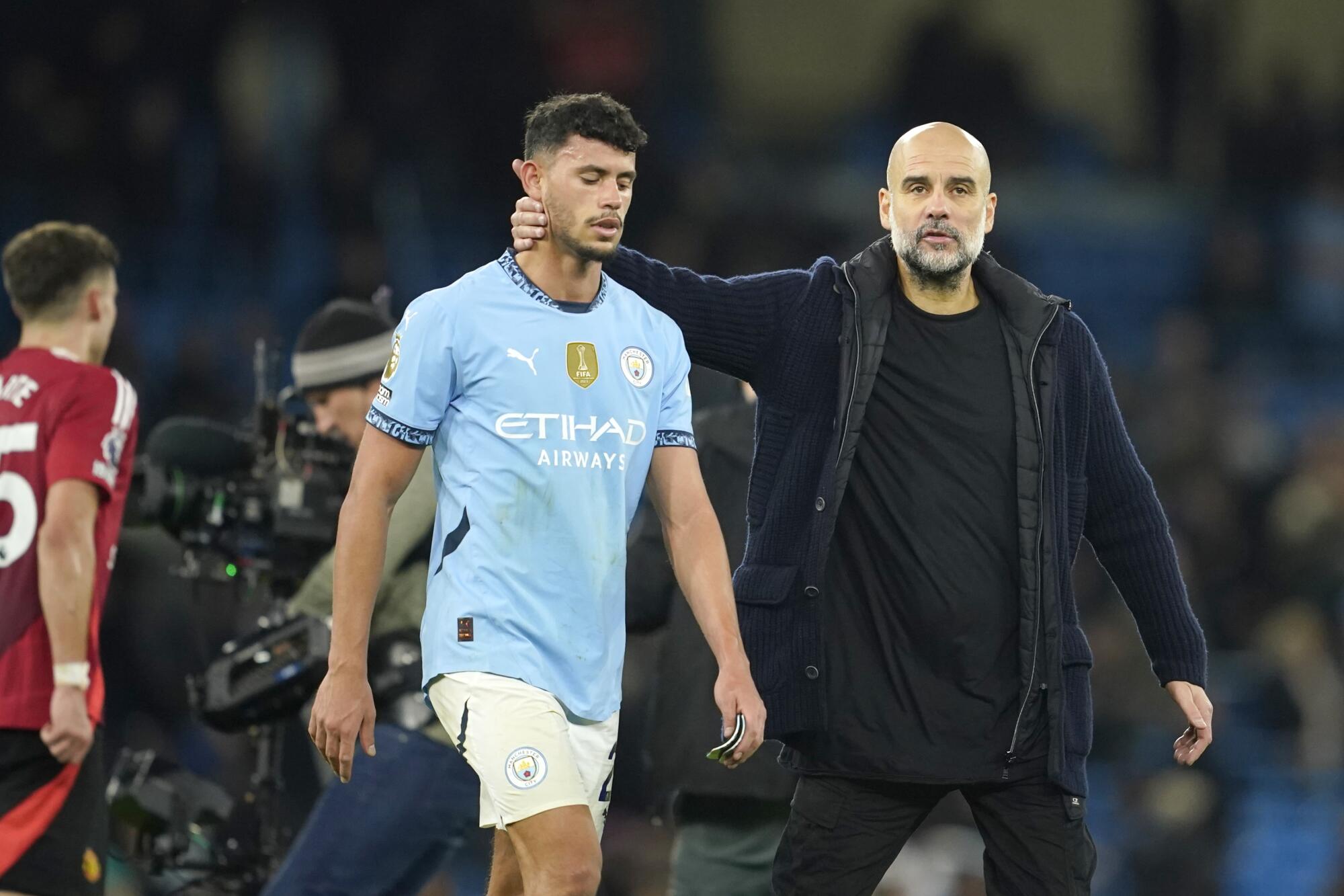 Manchester City coach Pep Guardiola, right, leaves the field with Matheus Nunes after a match.