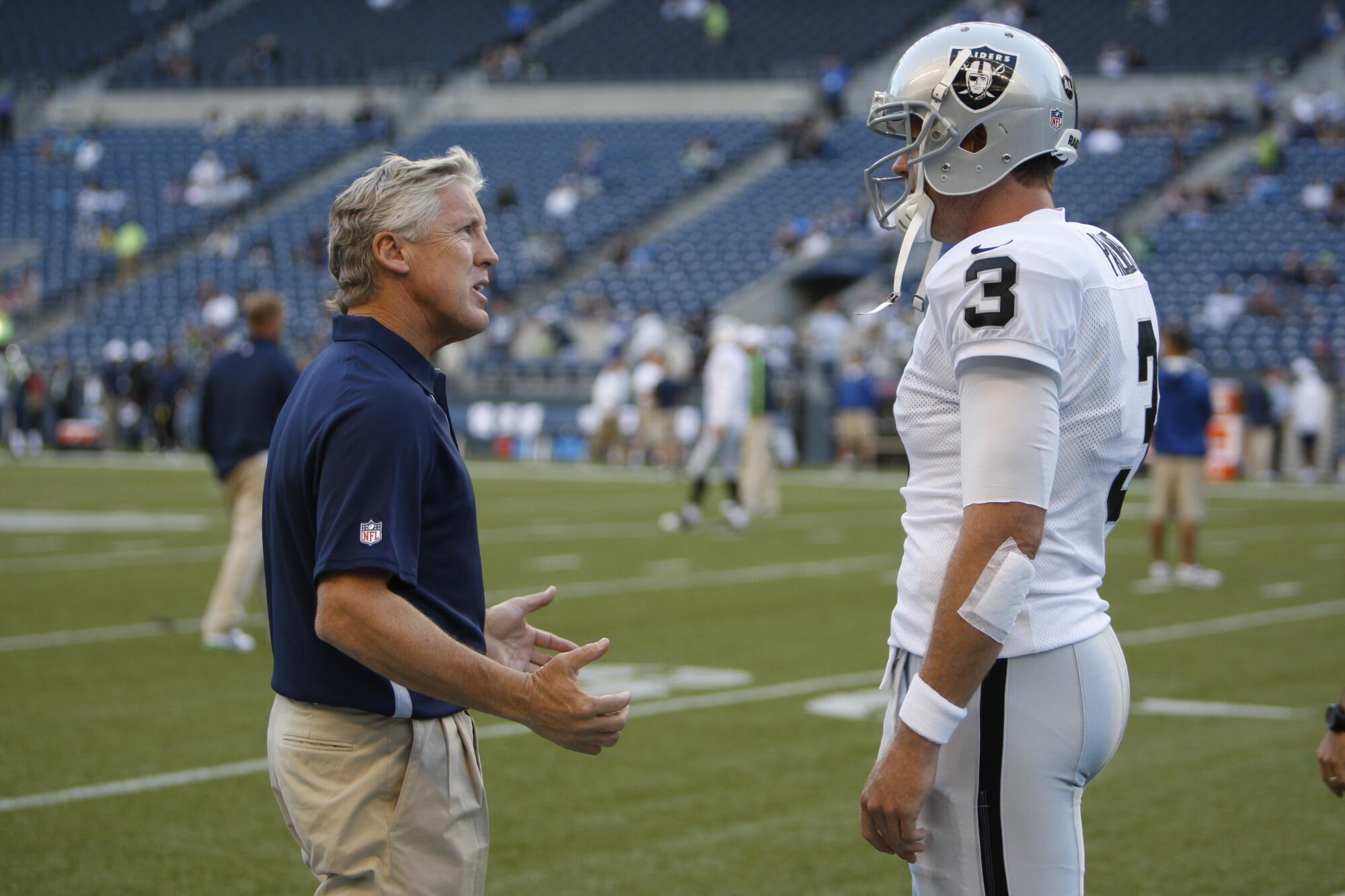 Seahawks coach Pete Carroll, left, talks with Raiders quarterback Carson Palmer before a preseason game in 2012.