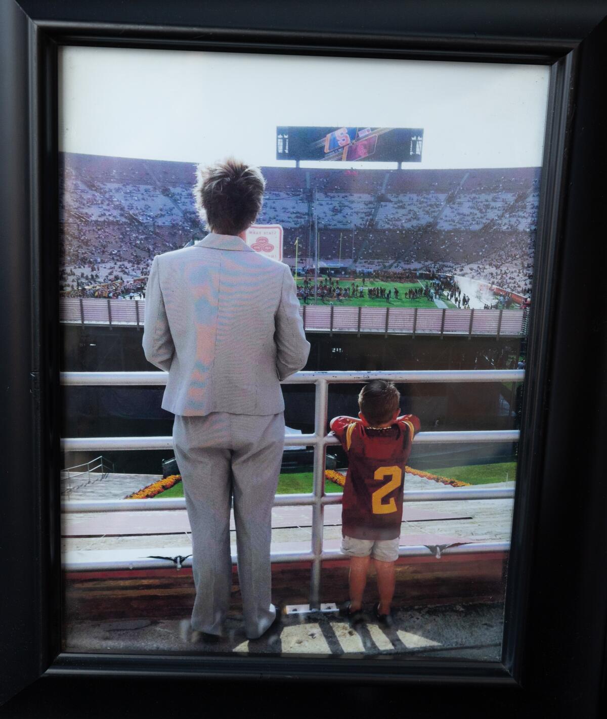 A framed photo shows the backs of a woman and a child in a stadium.