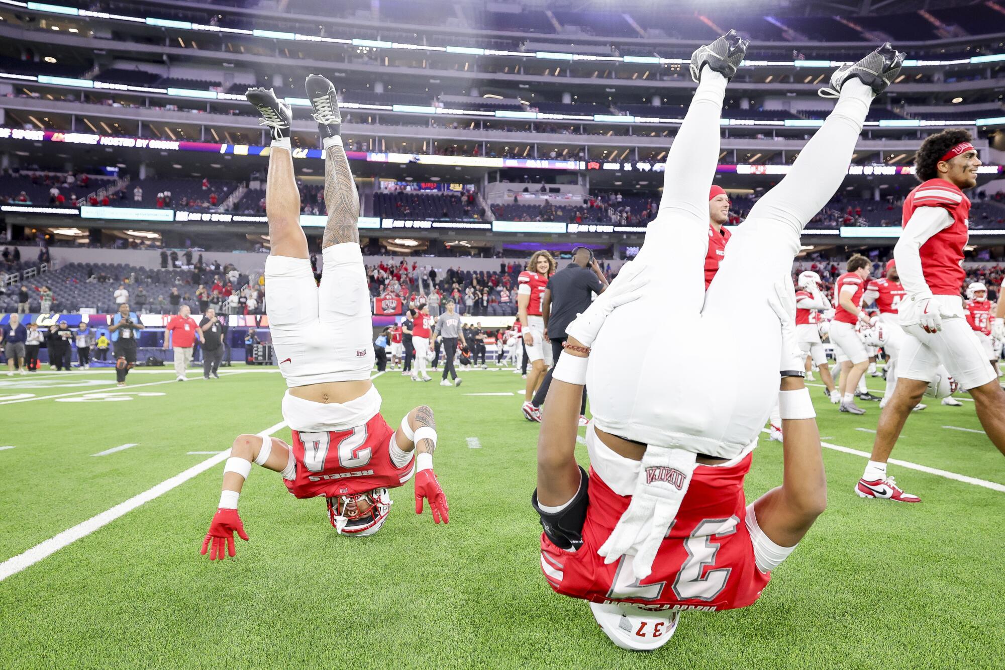 UNLV running back Darrien Jones and defensive back Devin Hartsuck stand on their heads on the field while celebrating