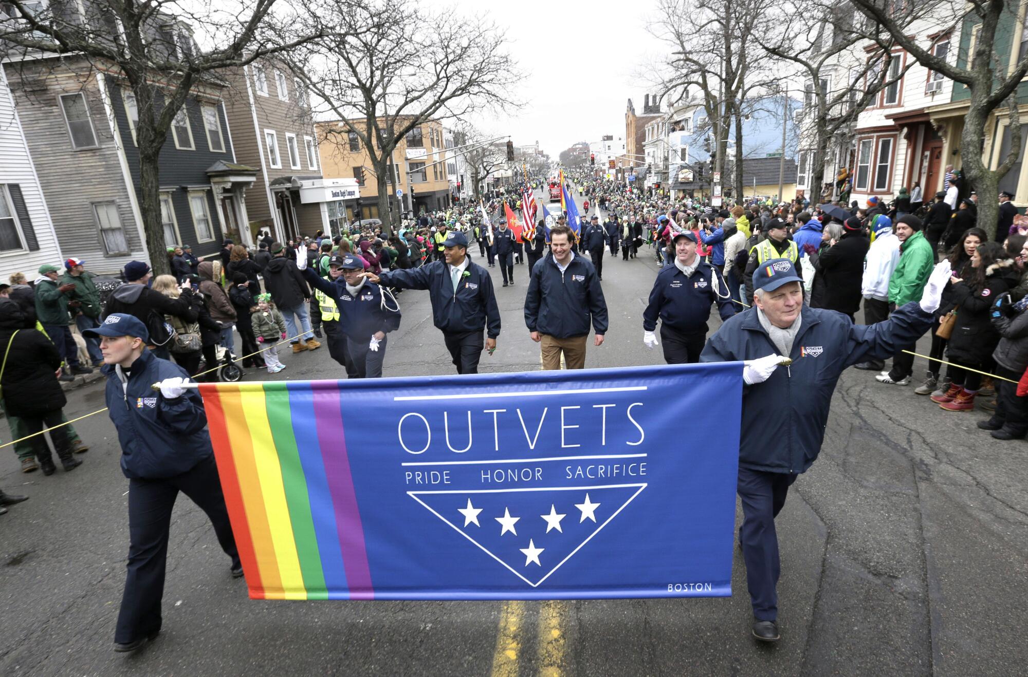 People in uniform carry an Outvets sign during a parade 