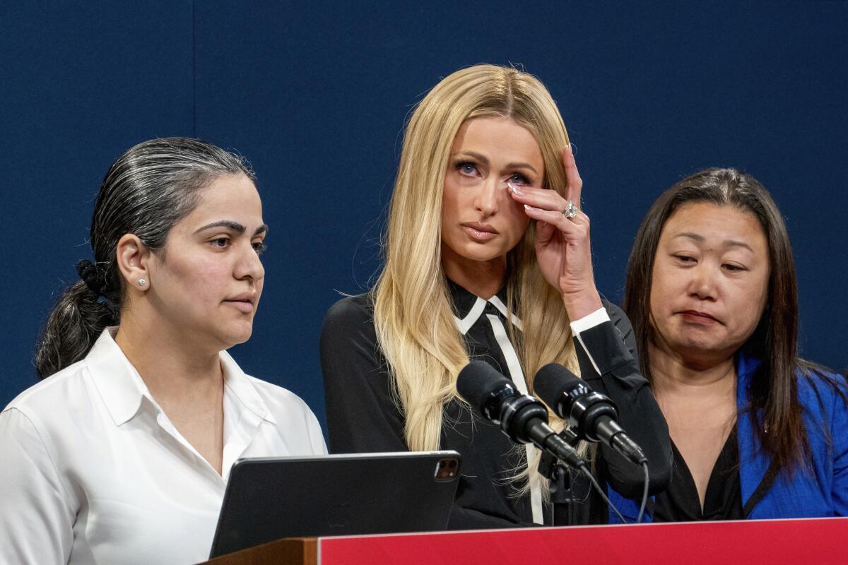 Paris Hilton wiping away tears at a news conference with two other women