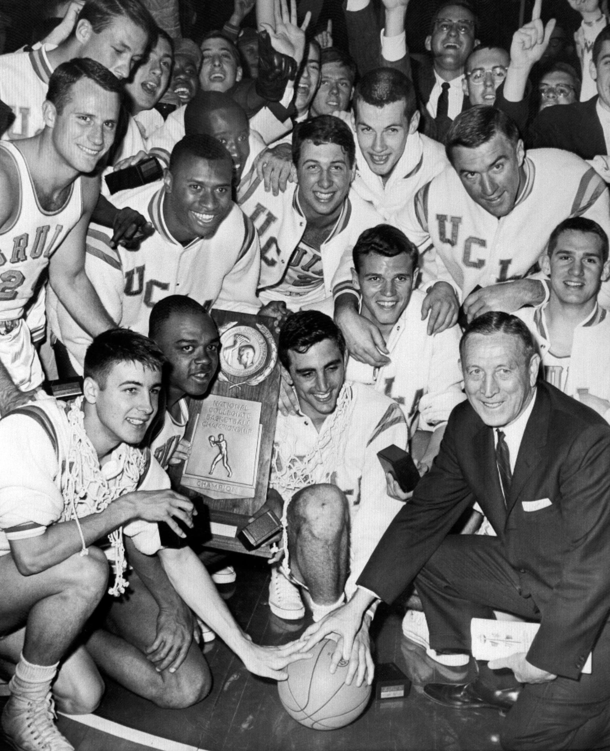 UCLA coach John Wooden and his players celebrating with their trophy after defeating Duke to win the 1964 national title