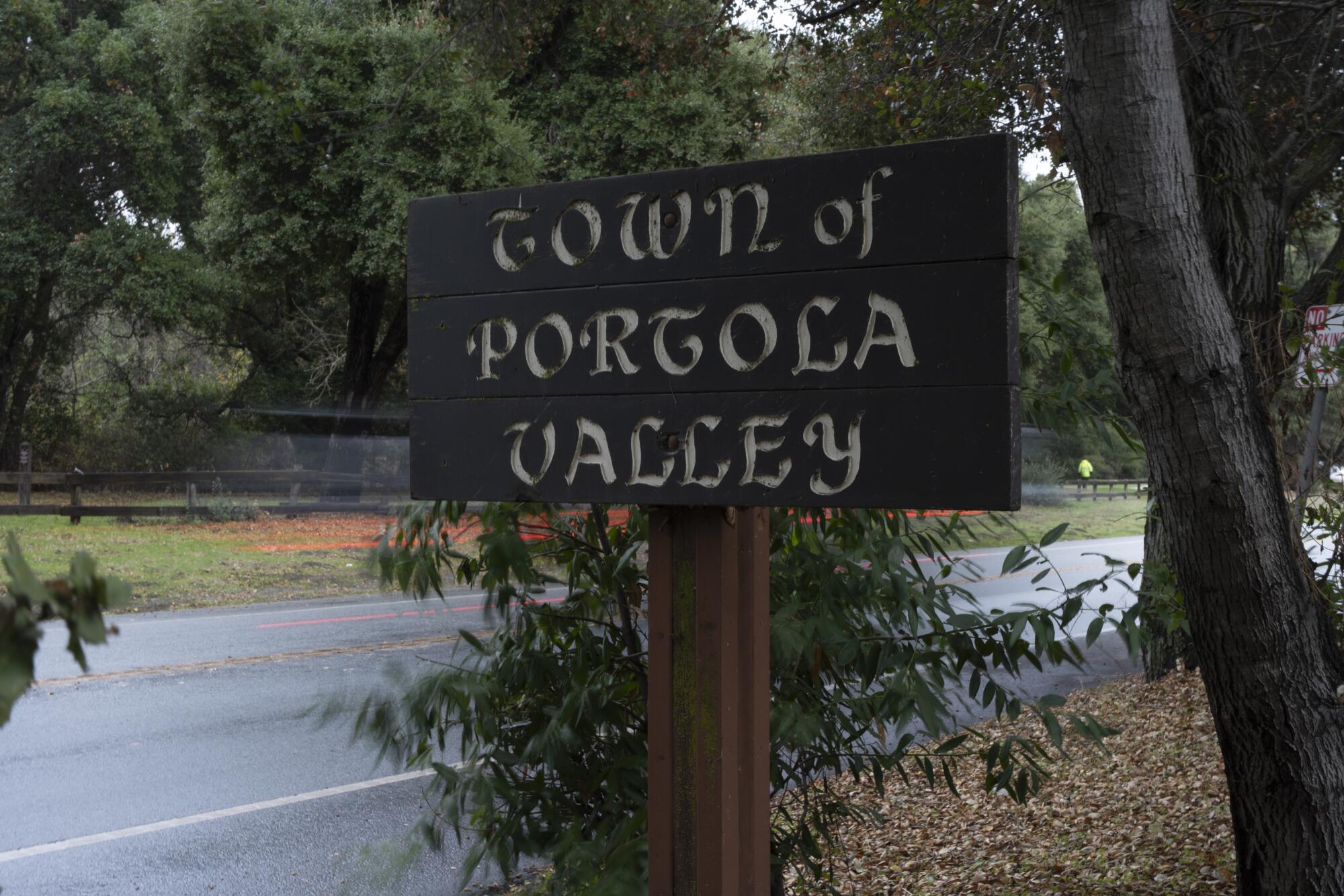 A car goes past a Town of Portola Valley sign on Alpine Road.