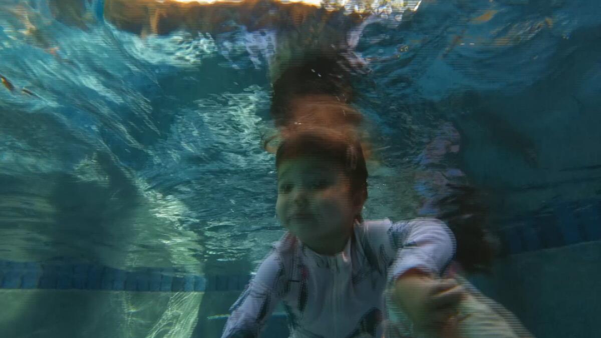 A toddler swims underwater in a scene from "A Swim Lesson." 