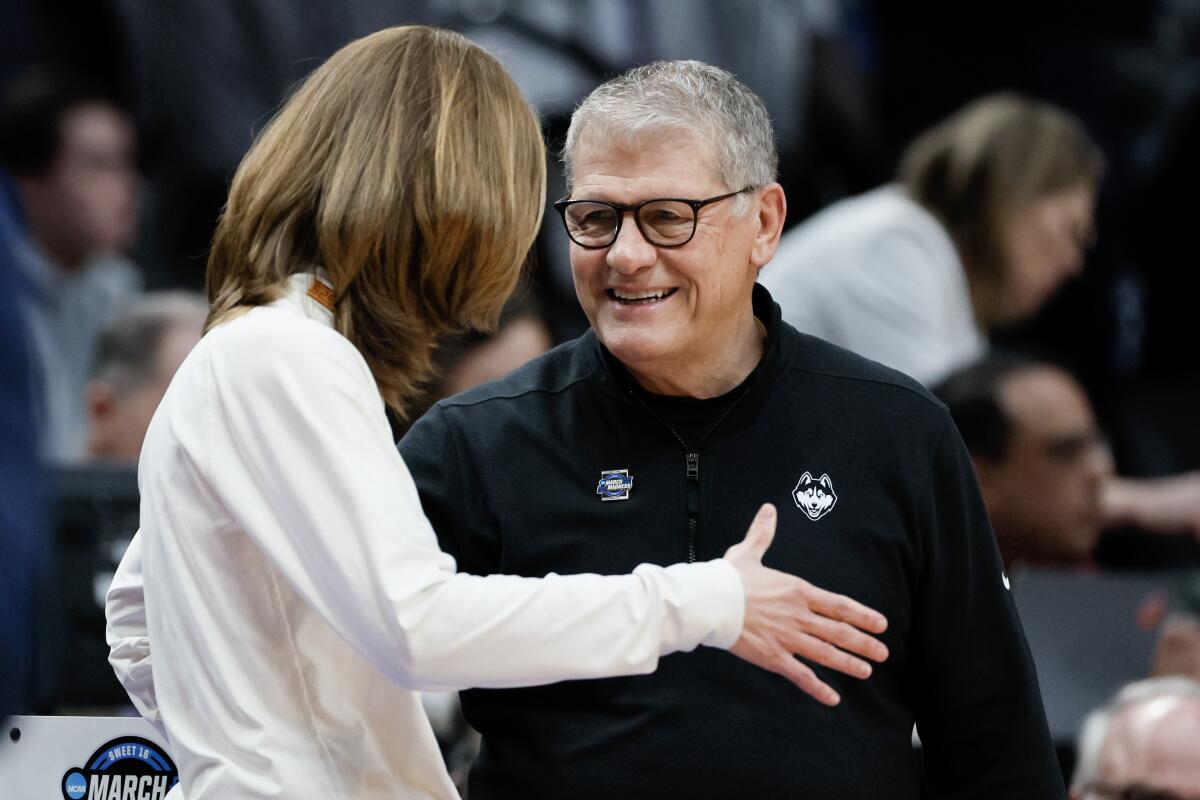 USC coach Lindsay Gottlieb, left, greets Connecticut coach Geno Auriemma before a game.