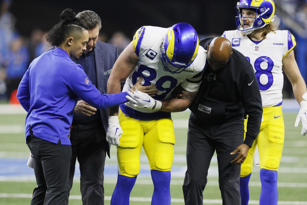 Rams tight end Tyler Higbee (89) is helped off the field after injuring his knee in a playoff game against the Lions.