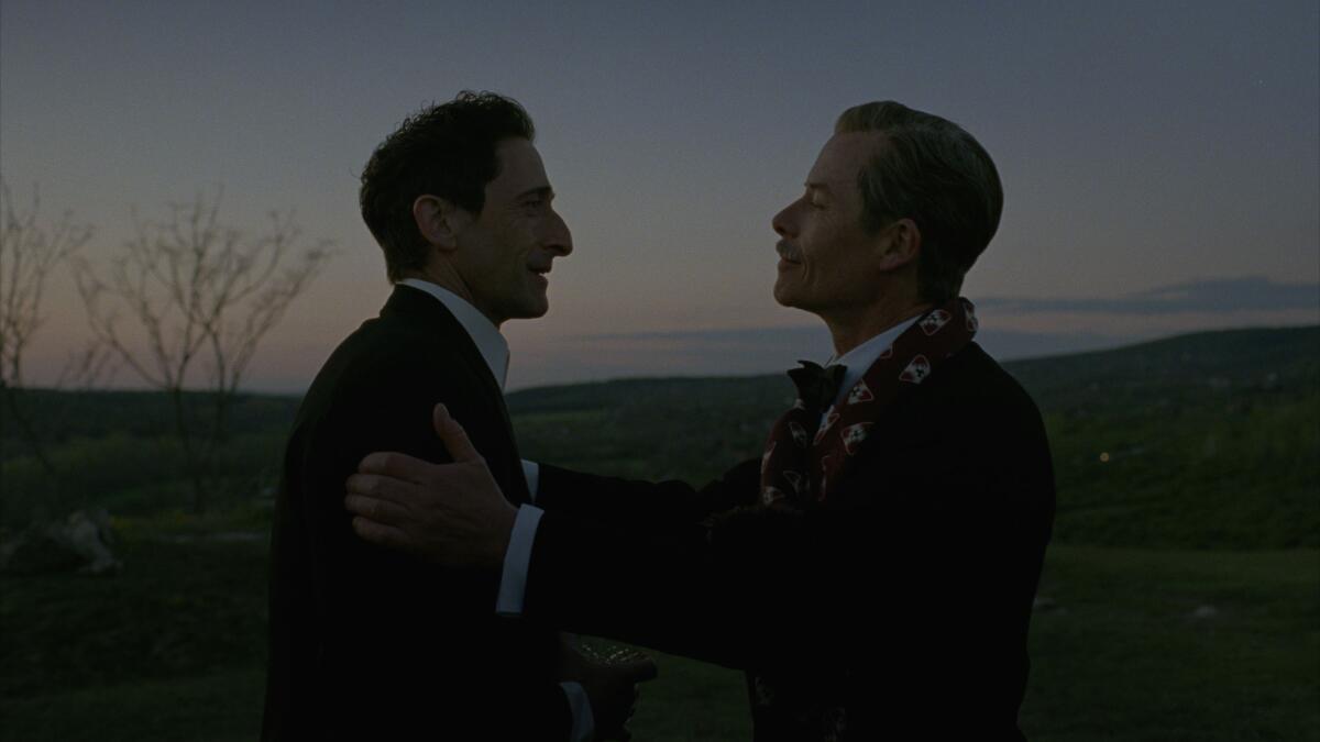 Two men speak on a hillside during twilight.