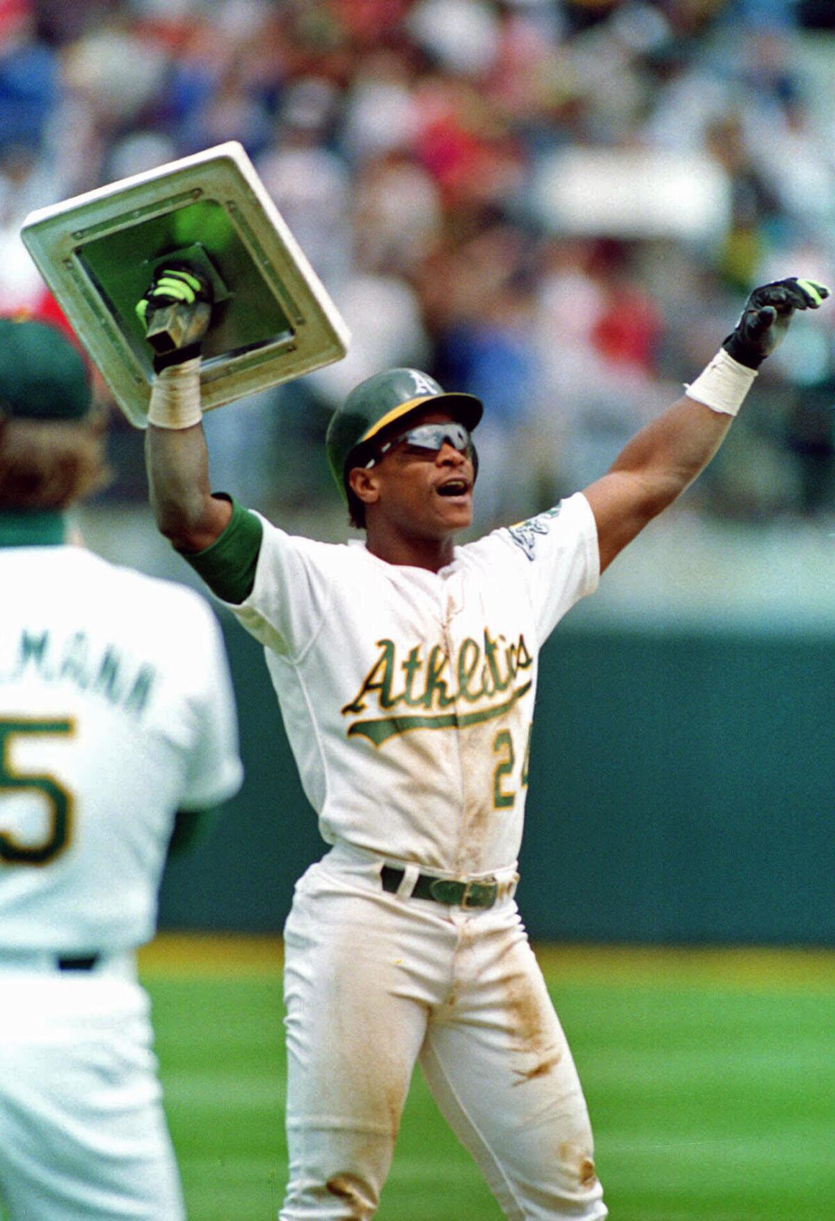 Rickey Henderson holds up third base after breaking Lou Brock's all-time career record for stolen bases on May 1, 1991.