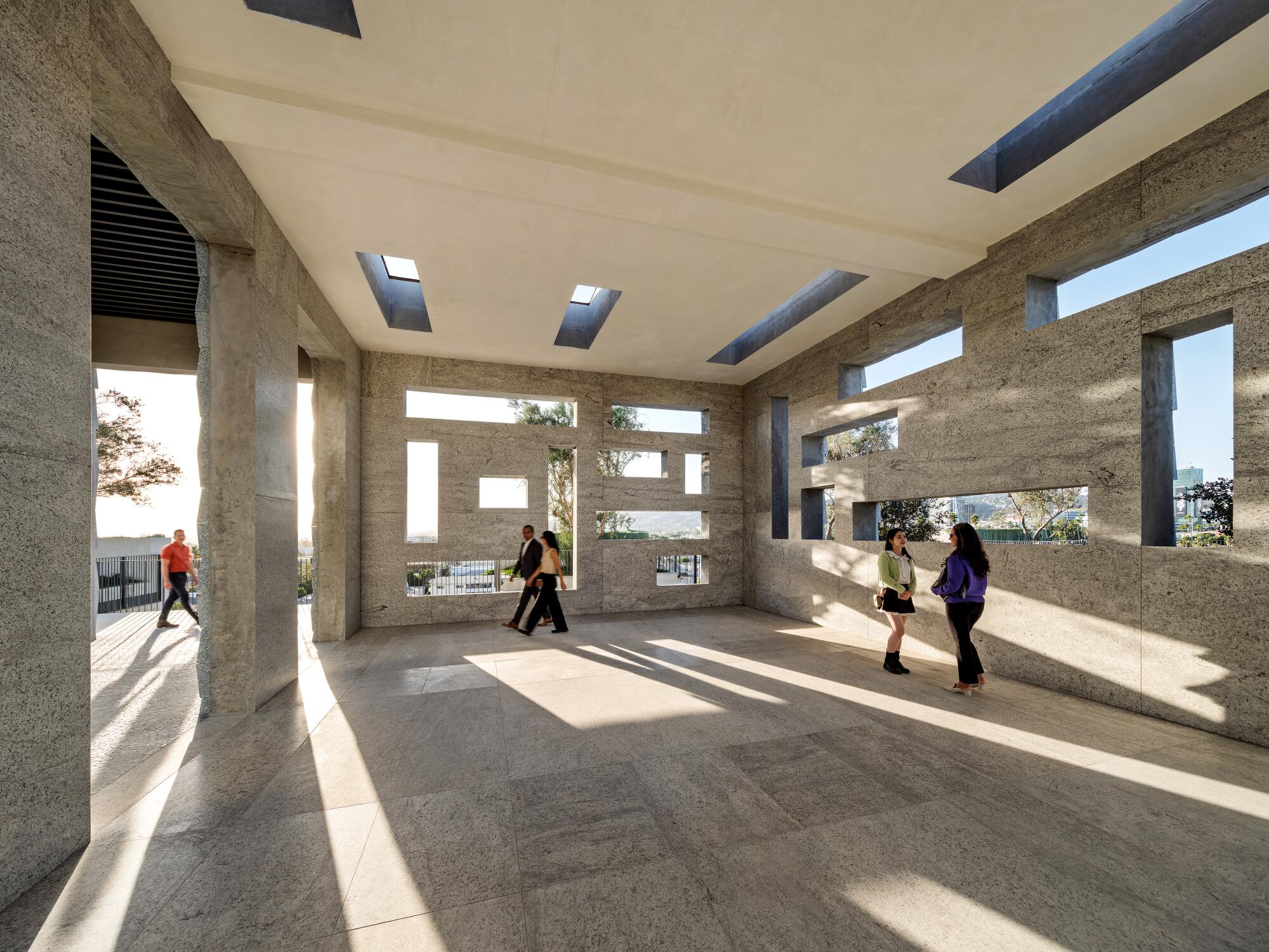 People inside a concrete structure whose walls are punctuated with varied openings