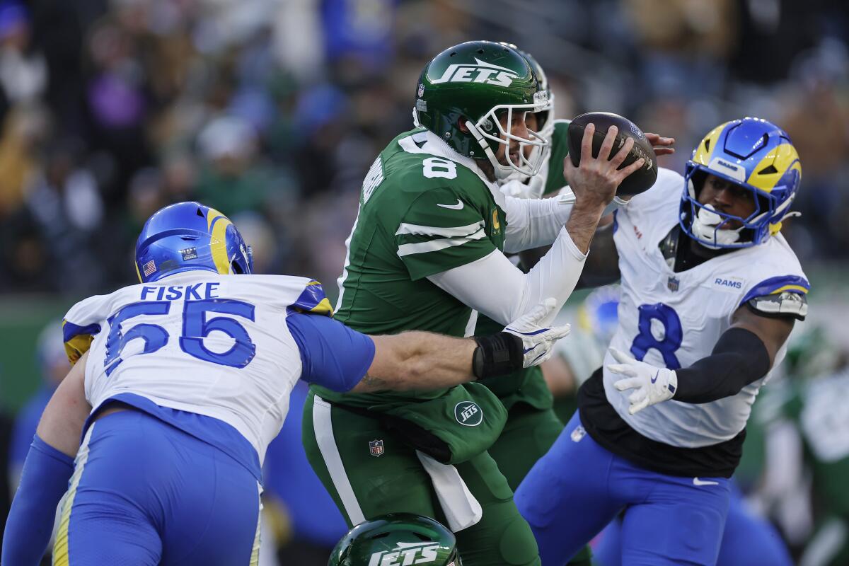 Rams Braden Fiske (55) and Jared Verse (8) sack Jets quarterback Aaron Rodgers (8).