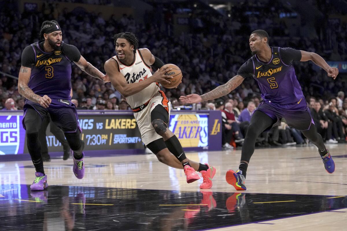 Detroit Pistons guard Jaden Ivey, center, drives past Lakers forwards Anthony Davis, left, and Cam Reddish.