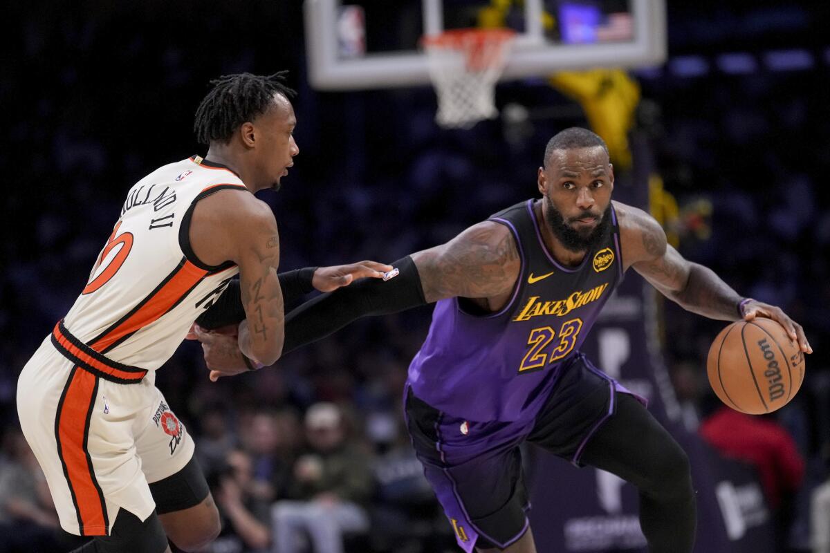 Lakers star LeBron James, right, drives against Detroit Pistons forward Ronald Holland II.