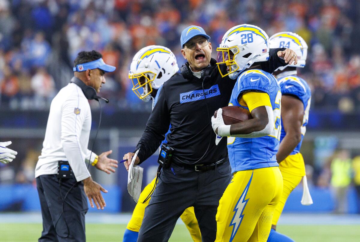 Chargers coach Jim Harbaugh hugs Hassan Haskins (28) after his touchdown against the Broncos.