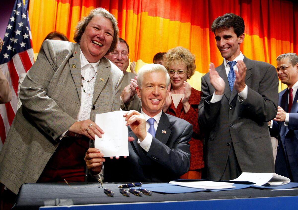 Gov. Gray Davis holds up signed legislation with Jackie Goldberg, left, in 2003