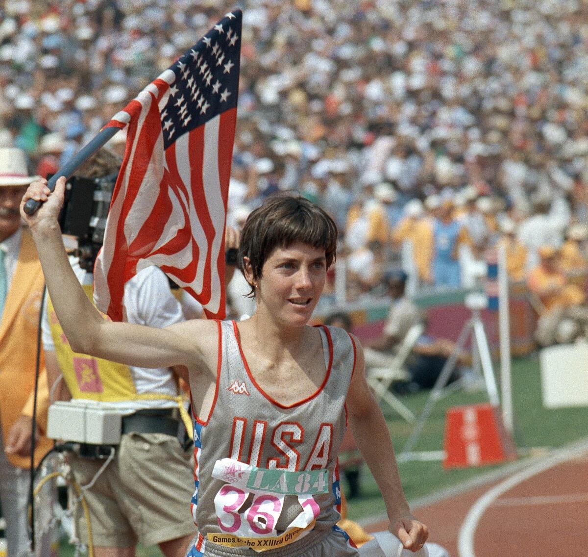 Joan Benoit Samuelson holds an American flag in celebration after winning gold in the women's marathon at the 1984 Olympics.