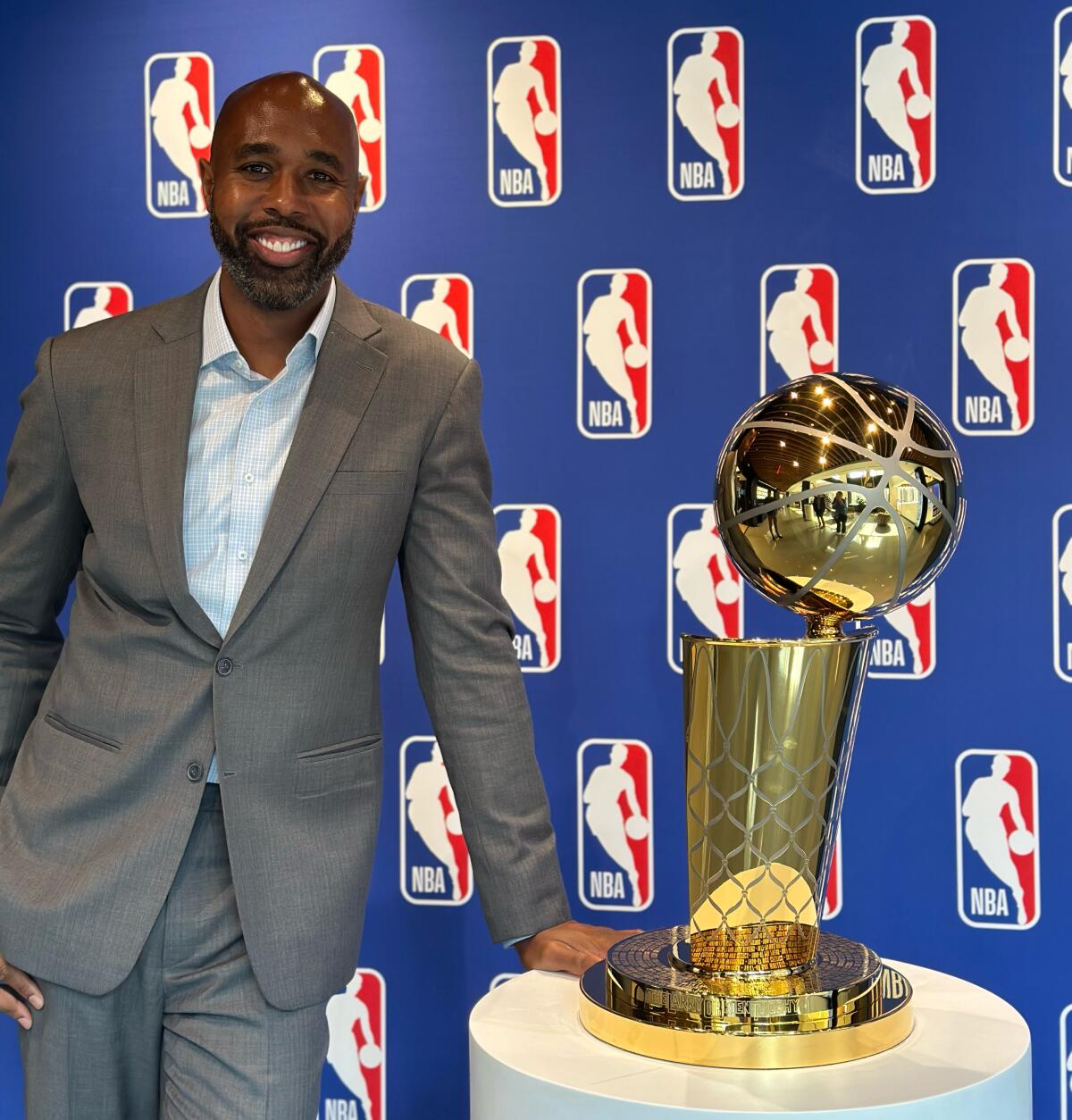 Albert Sanders Jr., NBA executive vice president, stands next to the Larry O’Brien Championship Trophy.