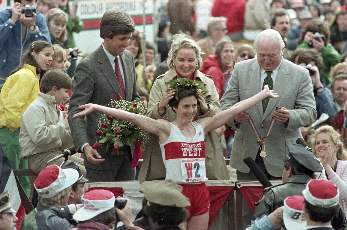 Joan Benoit Samuelson is crowned with a laurel wreath on a winner's podium; at left, then-Lt. Gov. John Kerry.