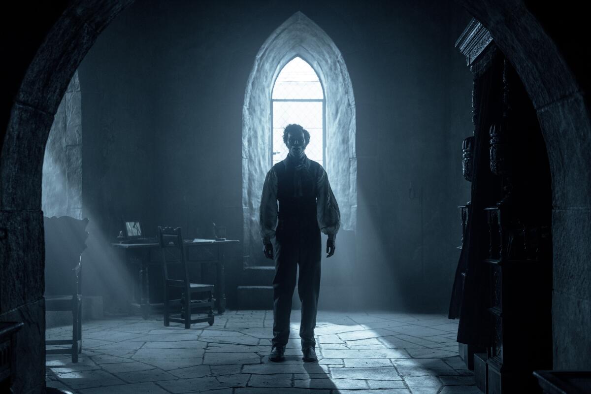 A man stands in a dimly lighted chamber.