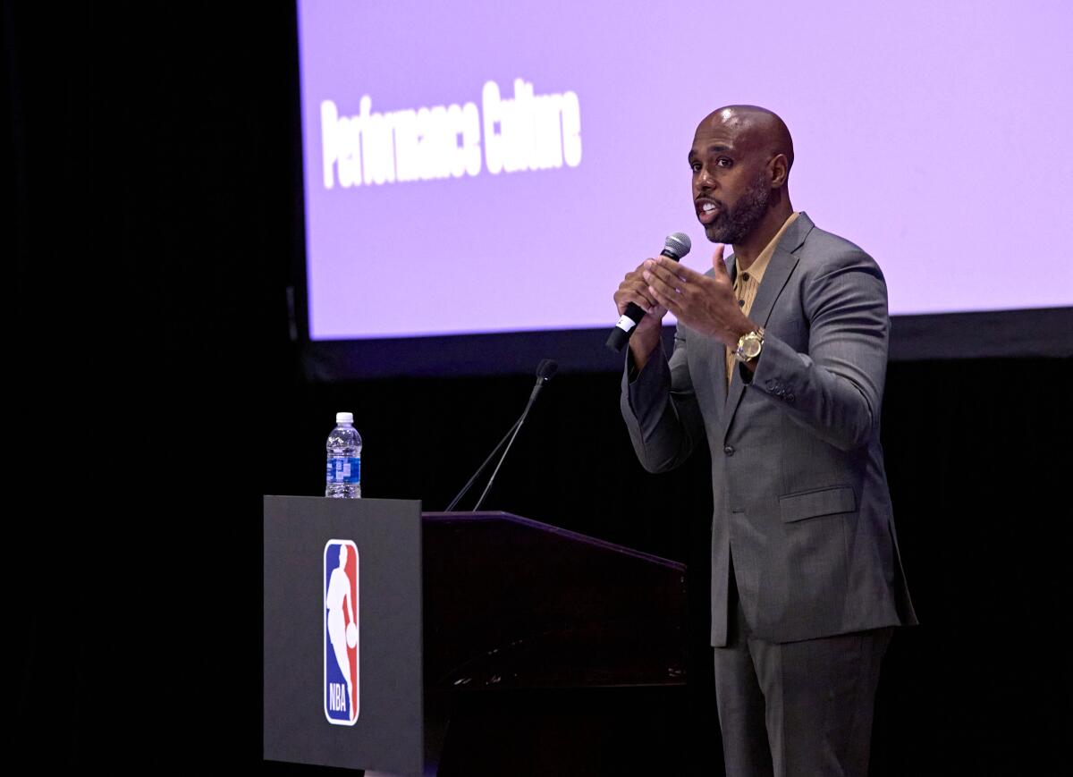 A man speaks onstage from a lectern with an NBA logo, the words "Performance Culture" in white on a purple screen behind him