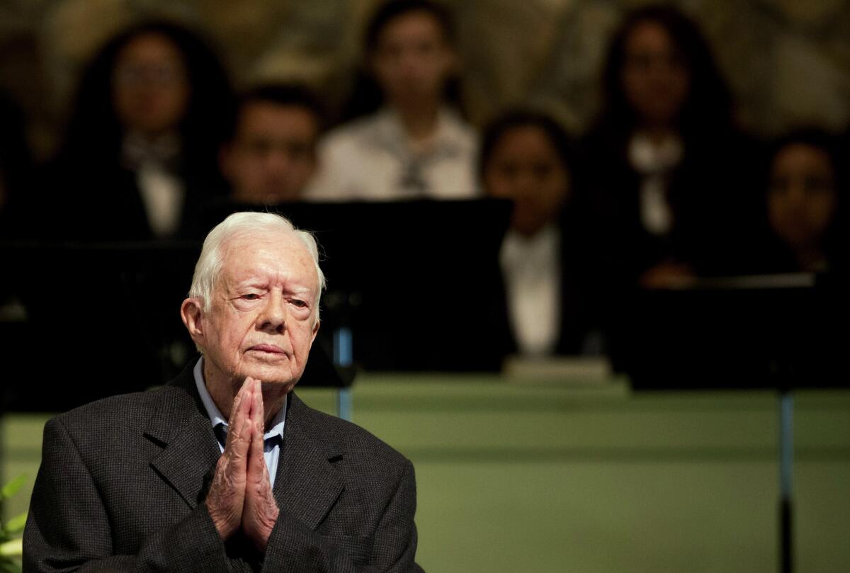 President Carter holds his hands together in prayer.