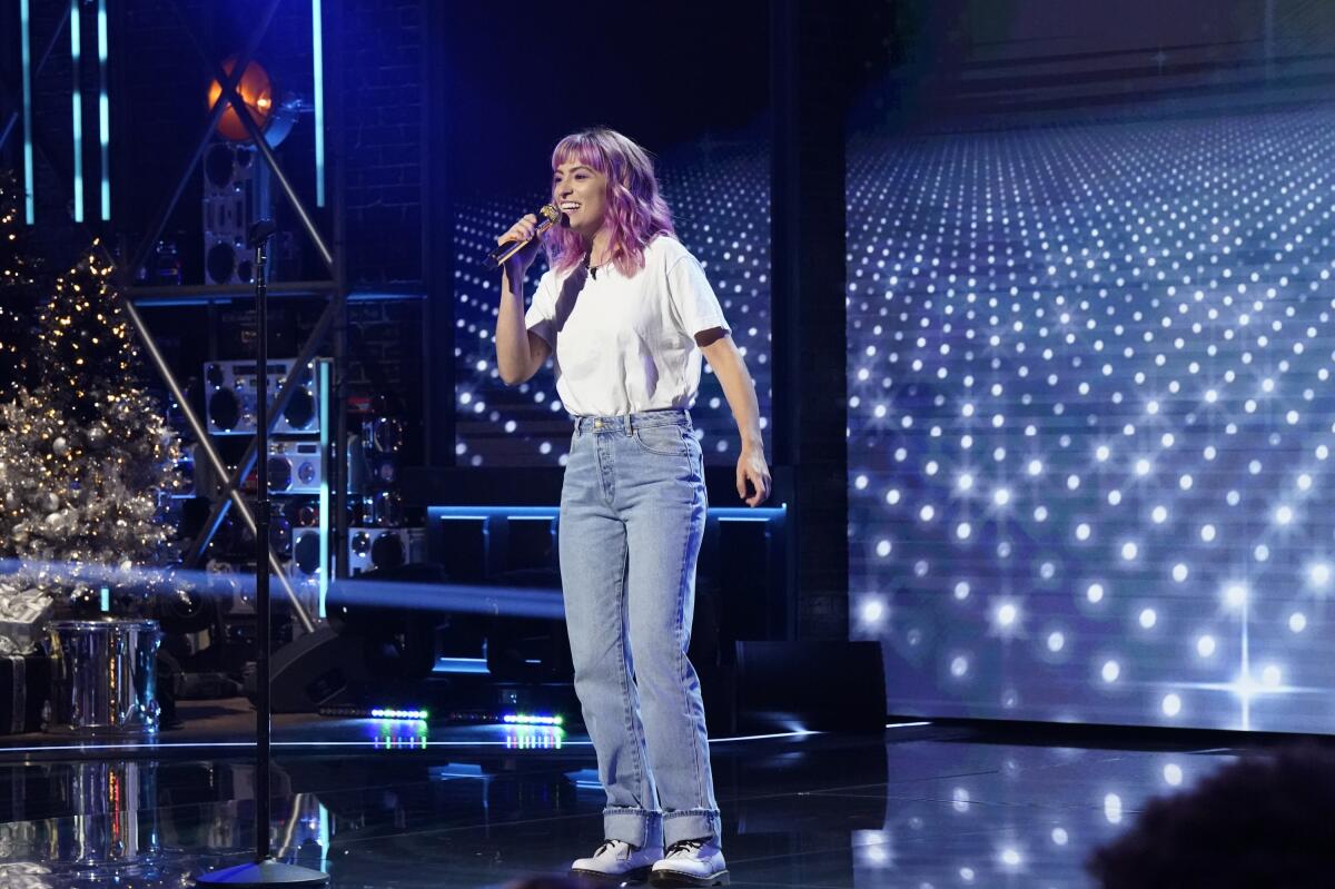 A woman in white T-shirt and jeans performs stand-up 