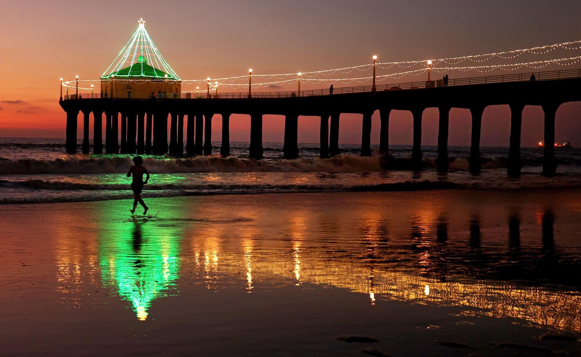 A man runs into the water at the Manhattan Beach Pier as Christmas approaches. 