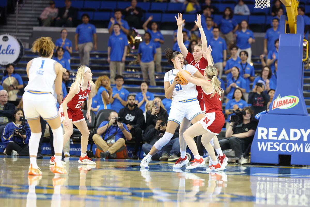 UCLA's Lauren Betts, left, tries to drive on Nebraska's Alexis Markowski and Allison Weidner.