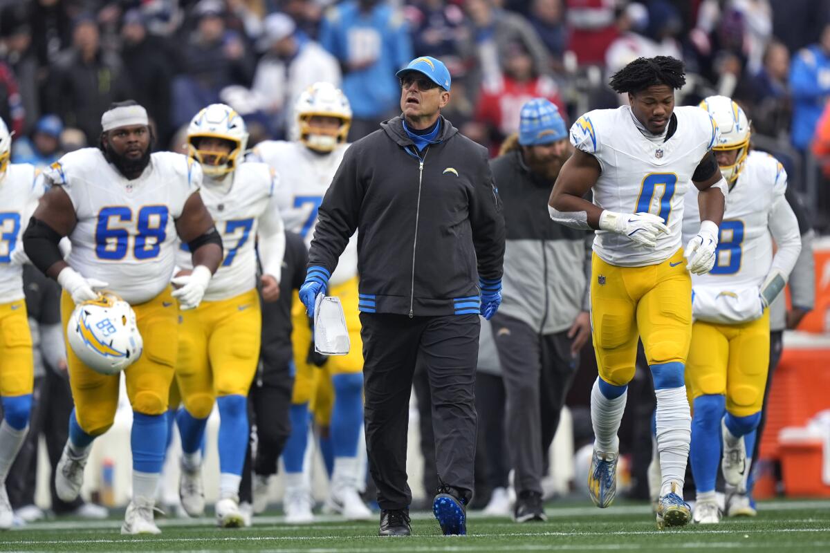 Chargers coach Jim Harbaugh walks off the field at halftime against the Patriots on Saturday.