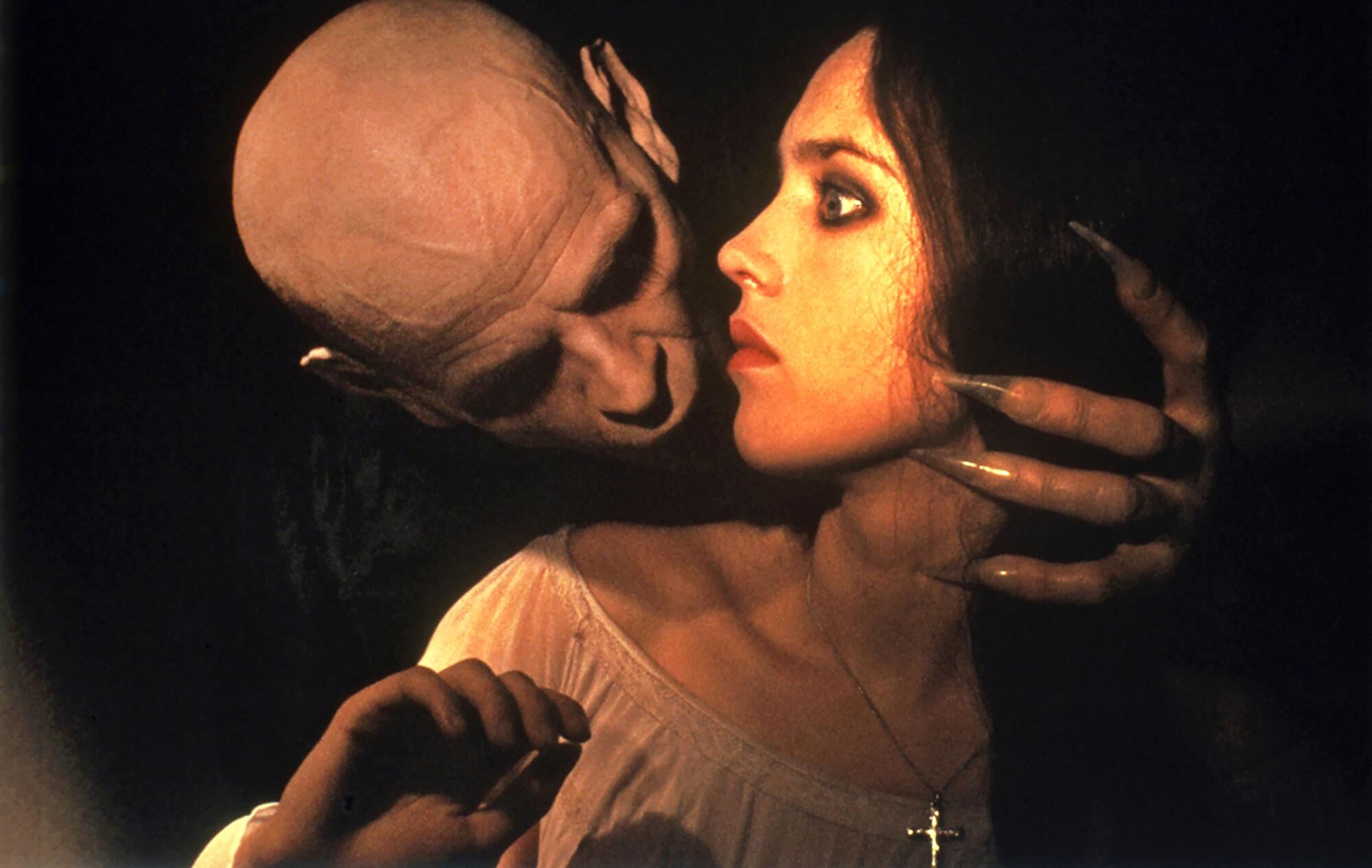 A bald and clawed creature leans in to bite a woman's neck in "Nosferatu the Vampyre."