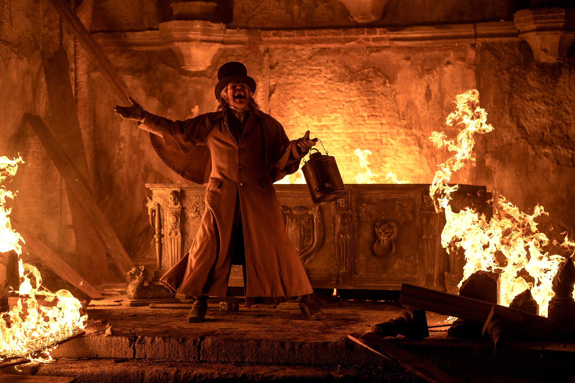 A man in 19th century clothes laughs wildly amid the flames of a burning house in "Nosferatu."