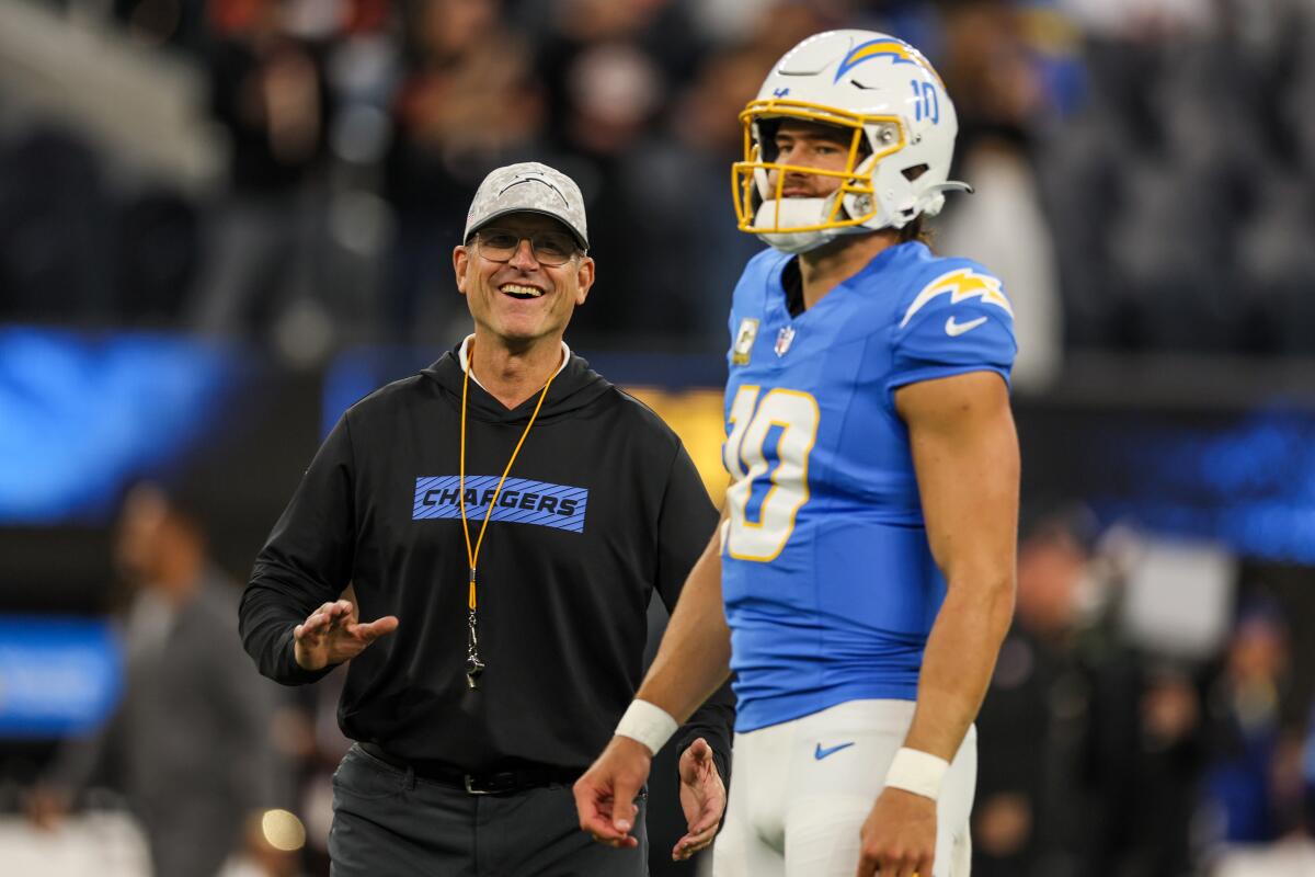 Chargers coach Jim Harbaugh smiles next to quarterback Justin Herbert before a game against the Cincinnati Bengals.