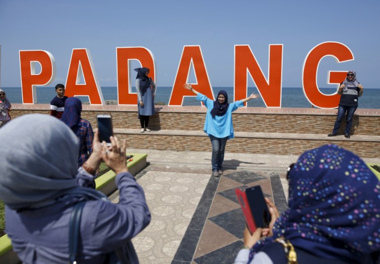 Visitors to the coastline take pictures with the Indian Ocean in the background a day after a 7.8 magnitude earthquake struck far out at sea in Padang, West Sumatra province, Indonesia March 3, 2016. REUTERS/Darren Whiteside TPX IMAGES OF THE DAY