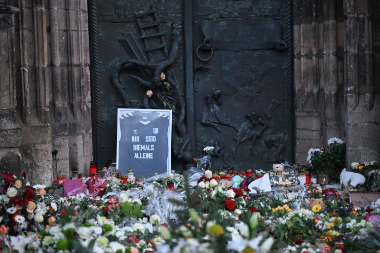 A FC Magdeburg football jersey with a message that reads "you will never be alone" is left with other tributes near the 'Alter Markt' Christmas market, where a man drove a car into the crowd through an emergency exit route on Friday evening, in Magdeburg, Germany, December 22, 2024. REUTERS/Annegret Hilse