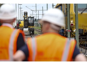 Workers near an excavator at the refurbishment work site of Deutsche Bahn AG's Riedbahn railway line in Walldorf, Germany. Photographer: Alex Kraus/Bloomberg