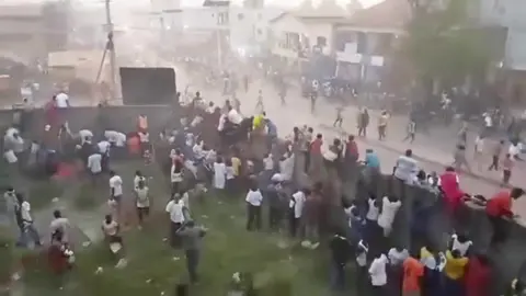 Reuters People scrambling climb over a wall at the stadium.