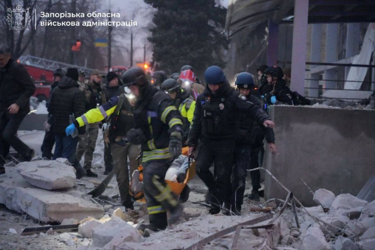 This handout photograph published on December 10, 2024, on the official Telegram channel of the head of the Zaporizhzhia Regional Military Administration Ivan Fedorov, shows rescuers and policemen carrying a wounded person at the site of a strike in the city of Zaporizhzhia, amid the Russian invasion of Ukraine. - A Russian strike on December 10, 2024, killed two people and wounded 11 others in the southern Ukrainian city of Zaporizhzhia, head of the Zaporizhzhia Regional Military Administration Ivan Fedorov said (Photo by Handout / Telegram /@ivan_fedorov_zp / AFP) / RESTRICTED TO EDITORIAL USE - MANDATORY CREDIT "AFP PHOTO / OFFICIAL TELEGRAM CHANNEL OF THE HEAD OF THE ZAPORIZHZHIA REGIONAL MILITARY ADMINISTRATION IVAN FEDOROV " - NO MARKETING NO ADVERTISING CAMPAIGNS - DISTRIBUTED AS A SERVICE TO CLIENTS