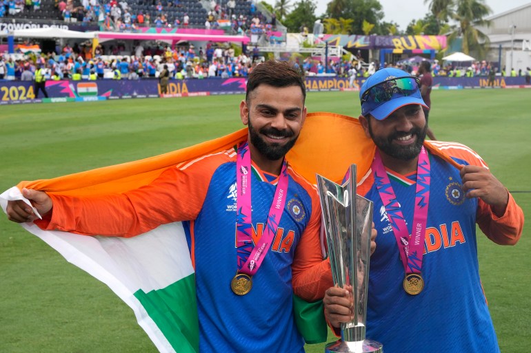 India's Virat Kohli, left, and captain Rohit Sharma pose with the winners trophy after defeating South Africa in the ICC Men's T20 World Cup final cricket match at Kensington Oval in Bridgetown, Barbados, Saturday, June 29, 2024. (AP Photo/Ricardo Mazalan)