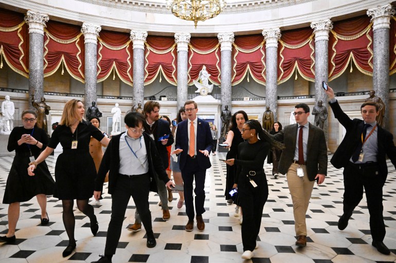 Members of Congress walk under the Capitol dome, surrounded by reporters and aides