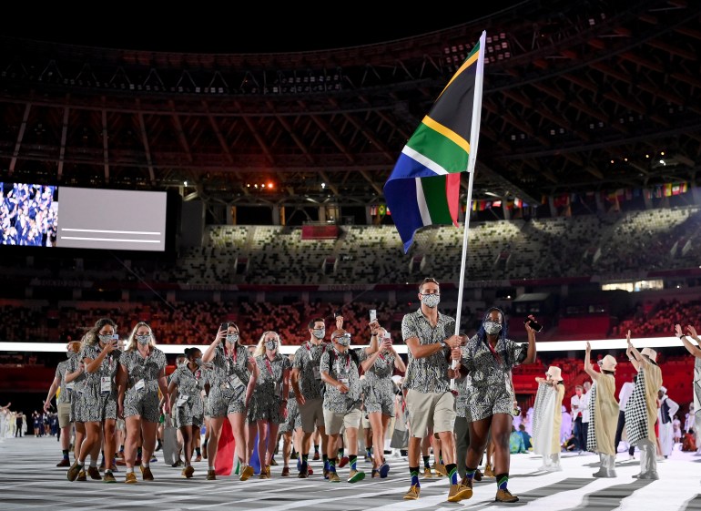 TOKYO, JAPAN - JULY 23: Flag bearers Phumelela Luphumlo Mbande and Chad Le Clos of Team South Africa lead their team out during the Opening Ceremony of the Tokyo 2020 Olympic Games at Olympic Stadium on July 23, 2021 in Tokyo, Japan. (Photo by Matthias Hangst/Getty Images)