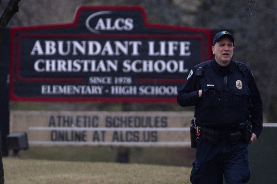 A police officer stands guard in front of Abundant Life Christian School on December 16