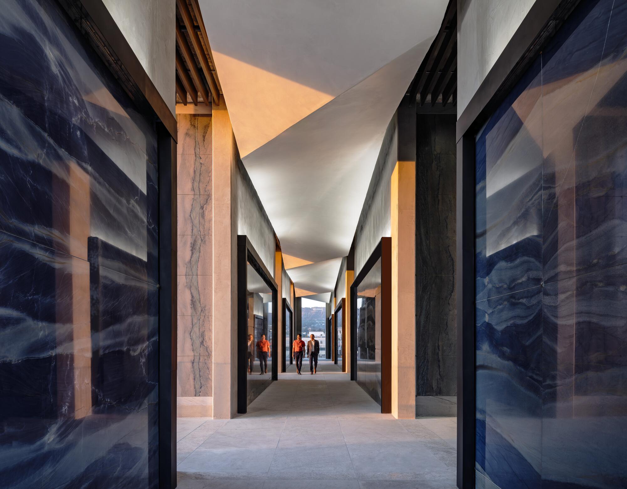 An interior corridor of a mausoleum is lined with panels of blue and white stone.