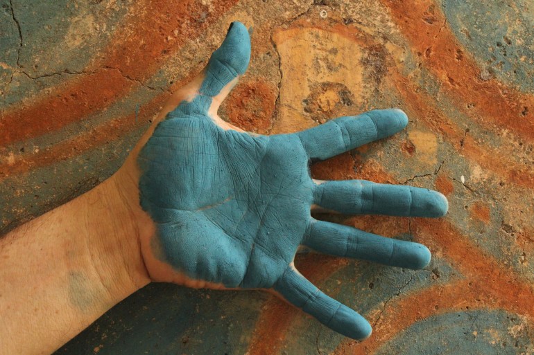 Luis May Ku, 49, places the back of his hand that is painted in Maya Blue against a fire kiln outside his home used to heat the formula that creates the pigment in Dzan, Yucatán, Mexico, on 9 September, 2024_.jpg