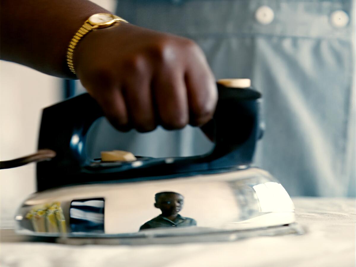 A boy is reflected in the mirrored chassis of an iron.