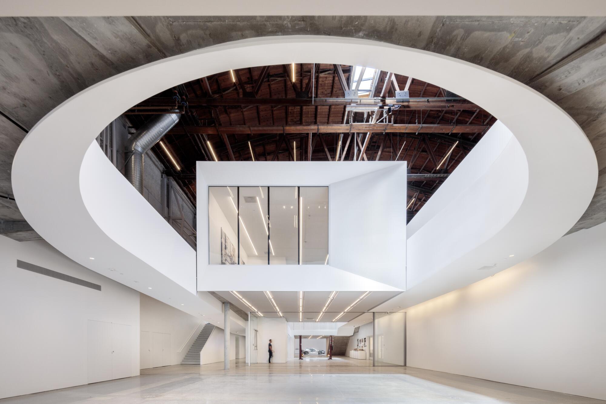 Inside a warehouse, a boxy second-floor room appears suspended in midair, flanked by  dramatic curved ramps. 