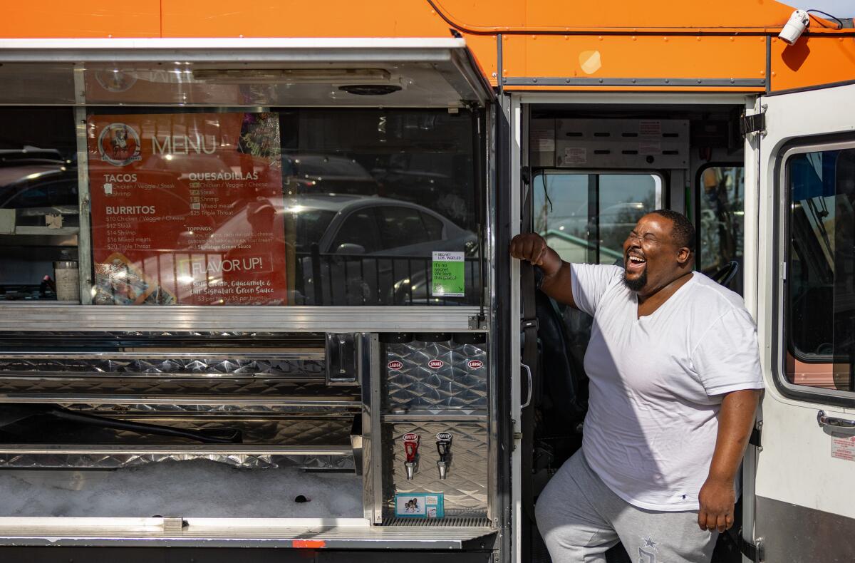 A man stands in the door of his taco truck