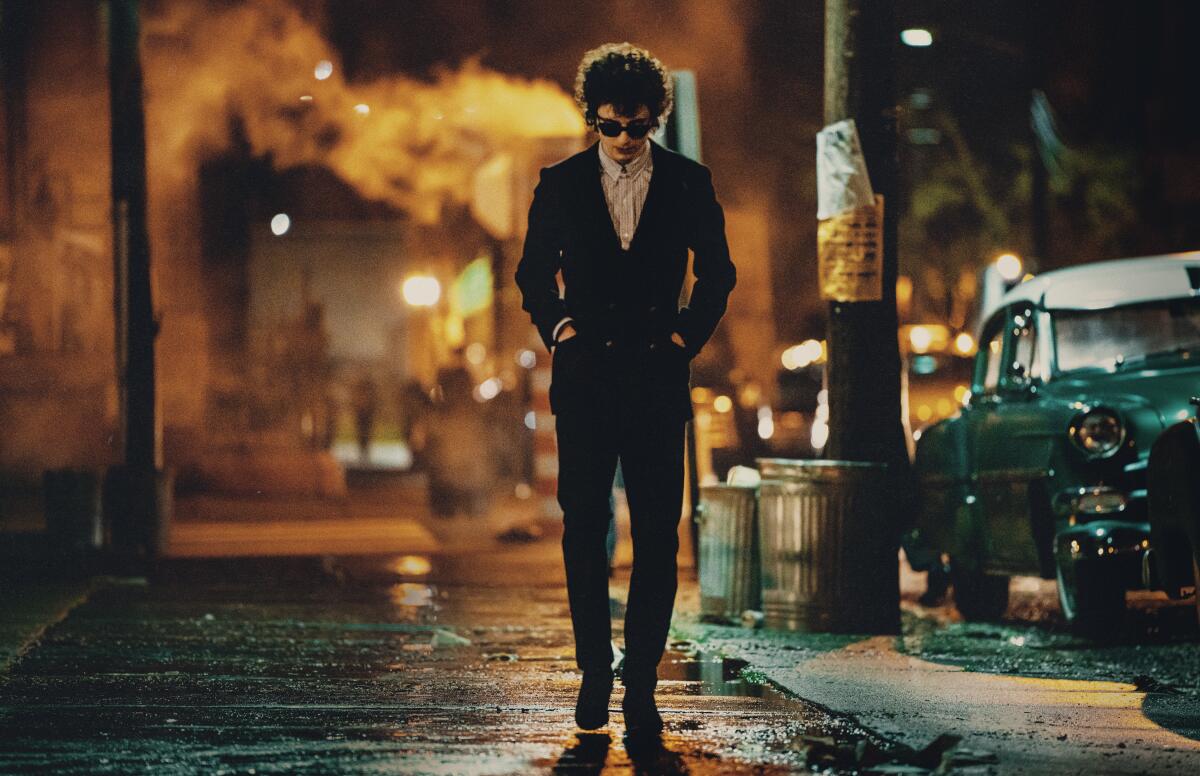 Timothee Chalamet walks alone, head down, on a night street in "A Complete Unknown."