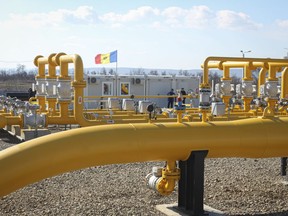 FILE - Men stand next to pipelines of the national natural gas distribution network outside Ungheni, Moldova, March 4, 2015.