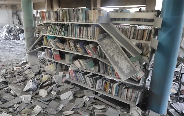 a photo of a a bookshelf destroyed, surrounded by rubble